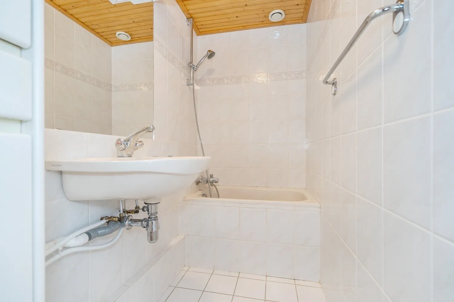 Badkamer voor de renovatie: gedateerde wastafel en betegeling