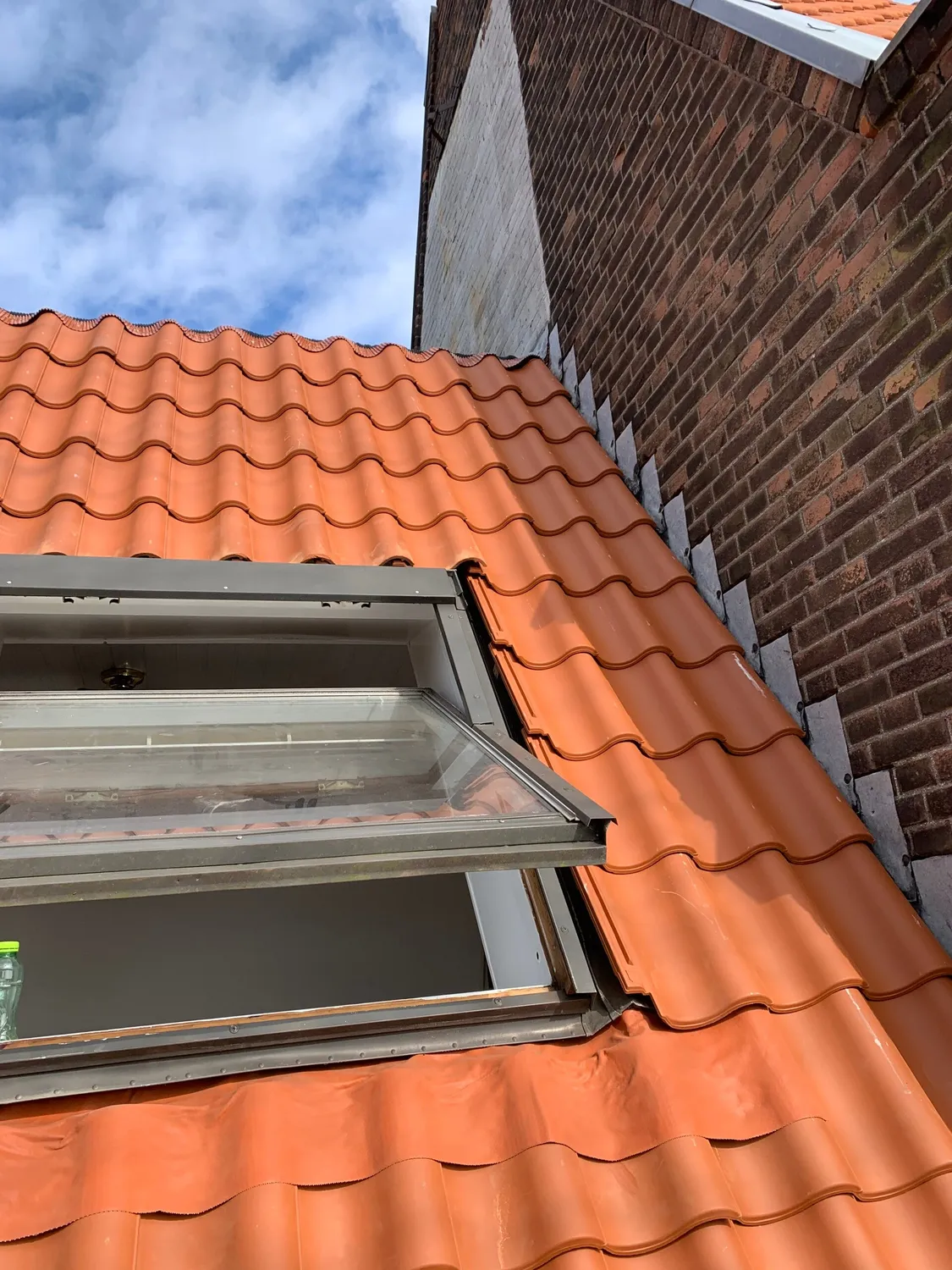 Nieuw dakraam in oranje pannendak naast de dakkapel