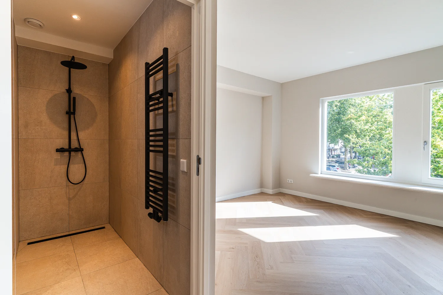 Badkamer met zwarte regendouche en handdoekradiator