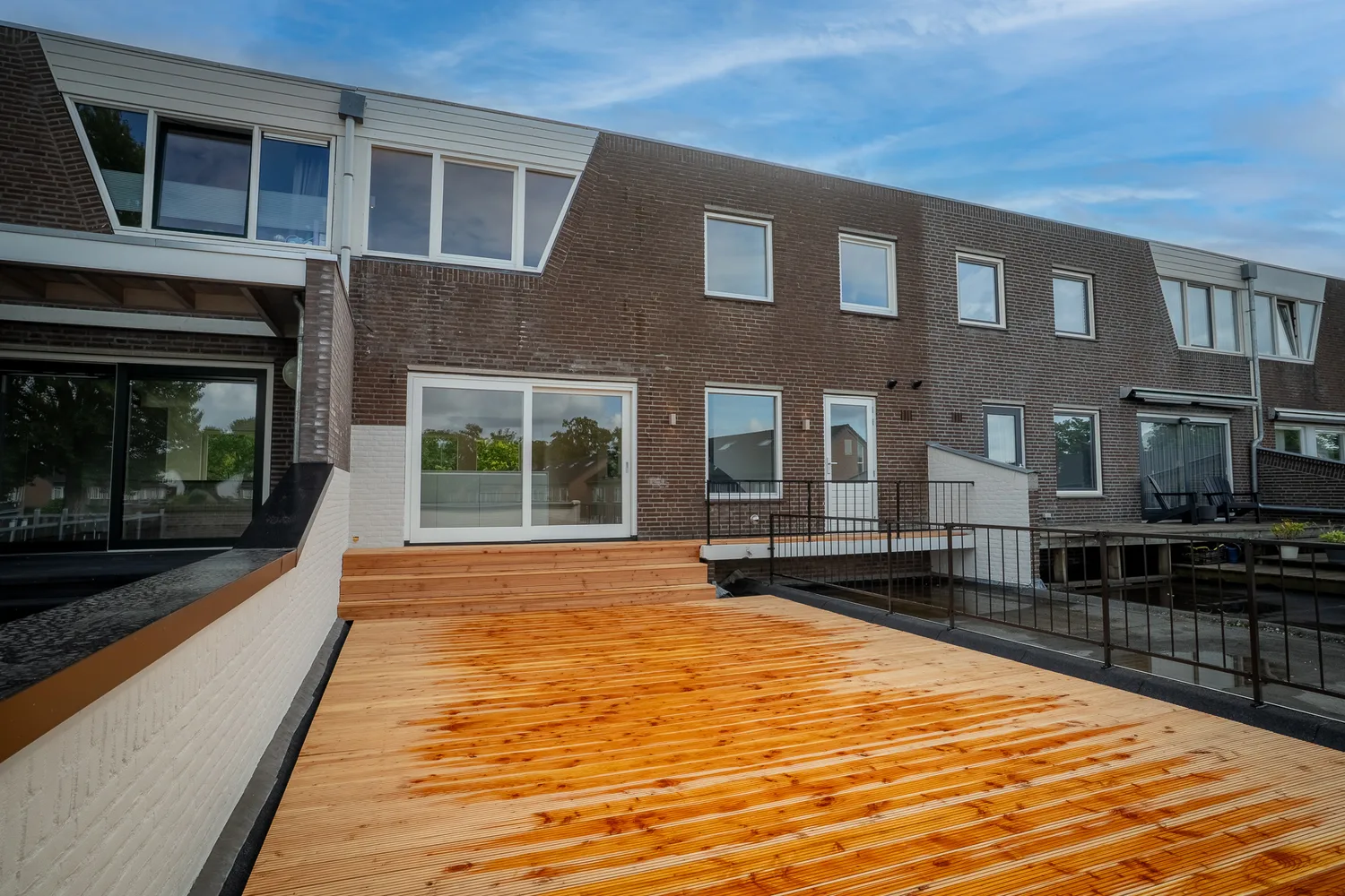 Achtergevel met dakterras en zwart hekwerk