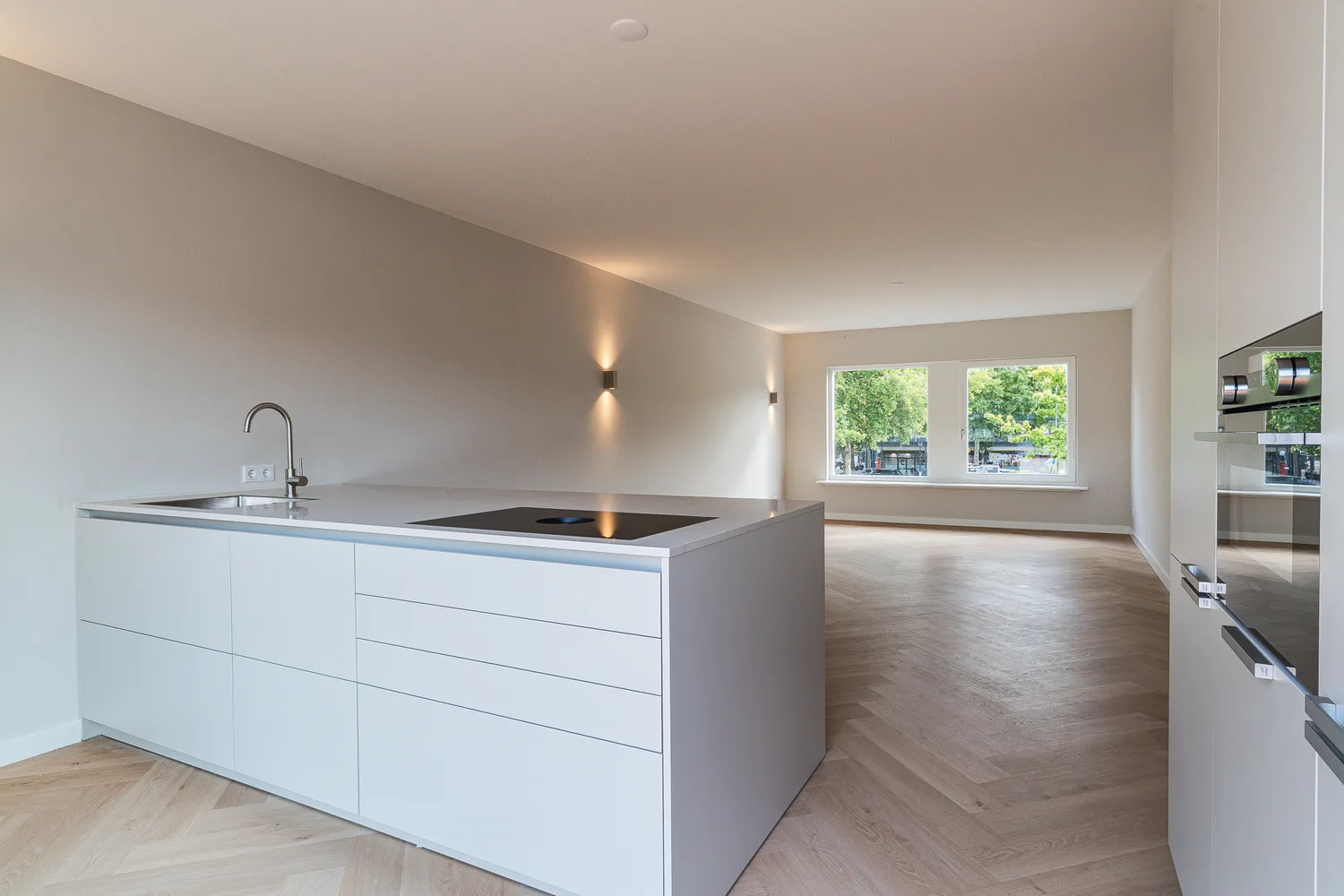 Witte keuken met kookeiland en wandlampen