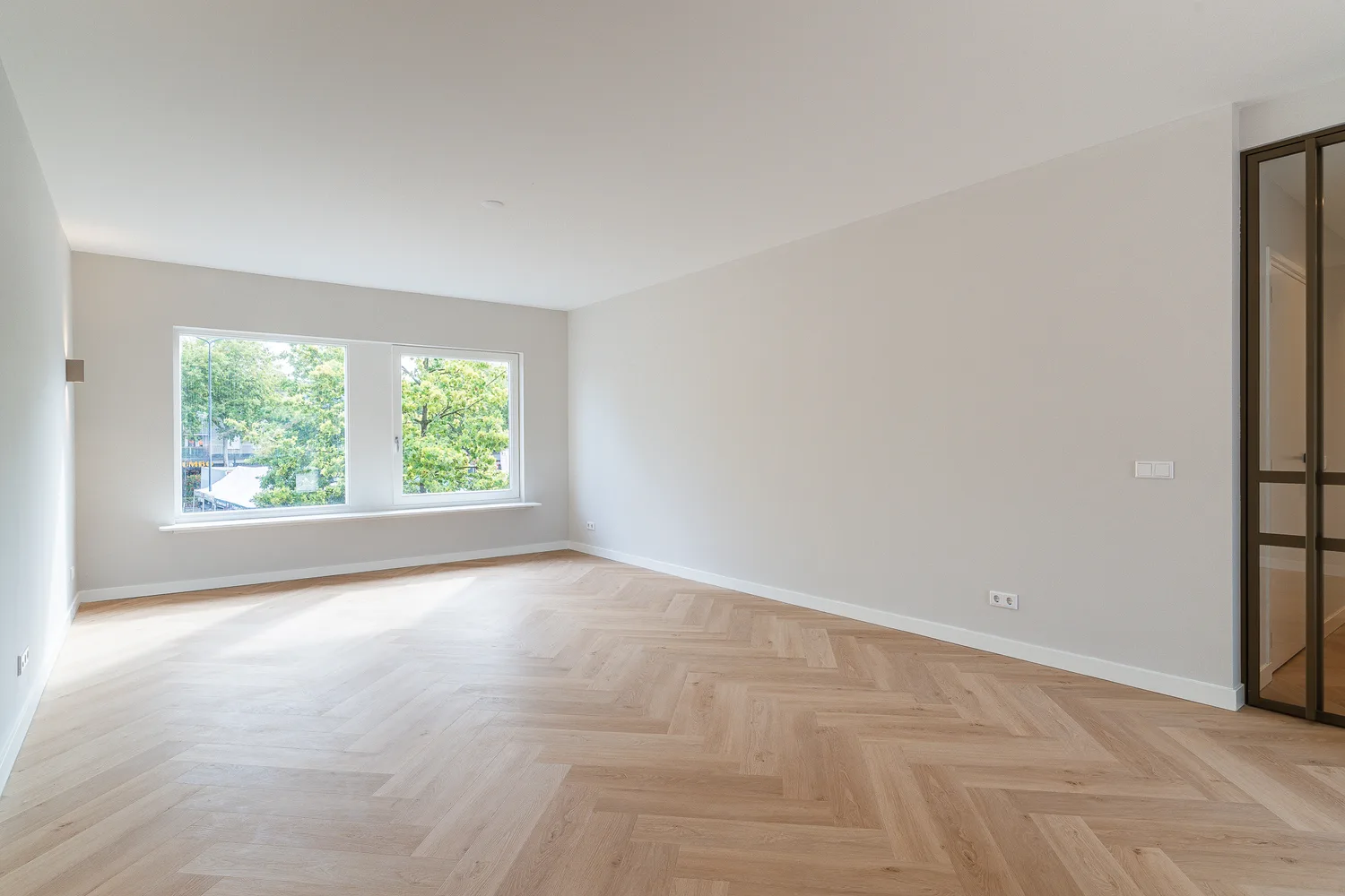 Woonkamer met visgraatvloer en groot raam