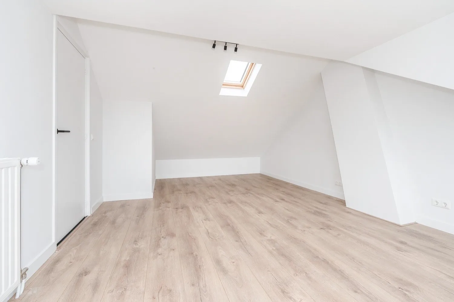 Zolder na de verbouwing: witte wanden, nieuwe vloer en dakraam