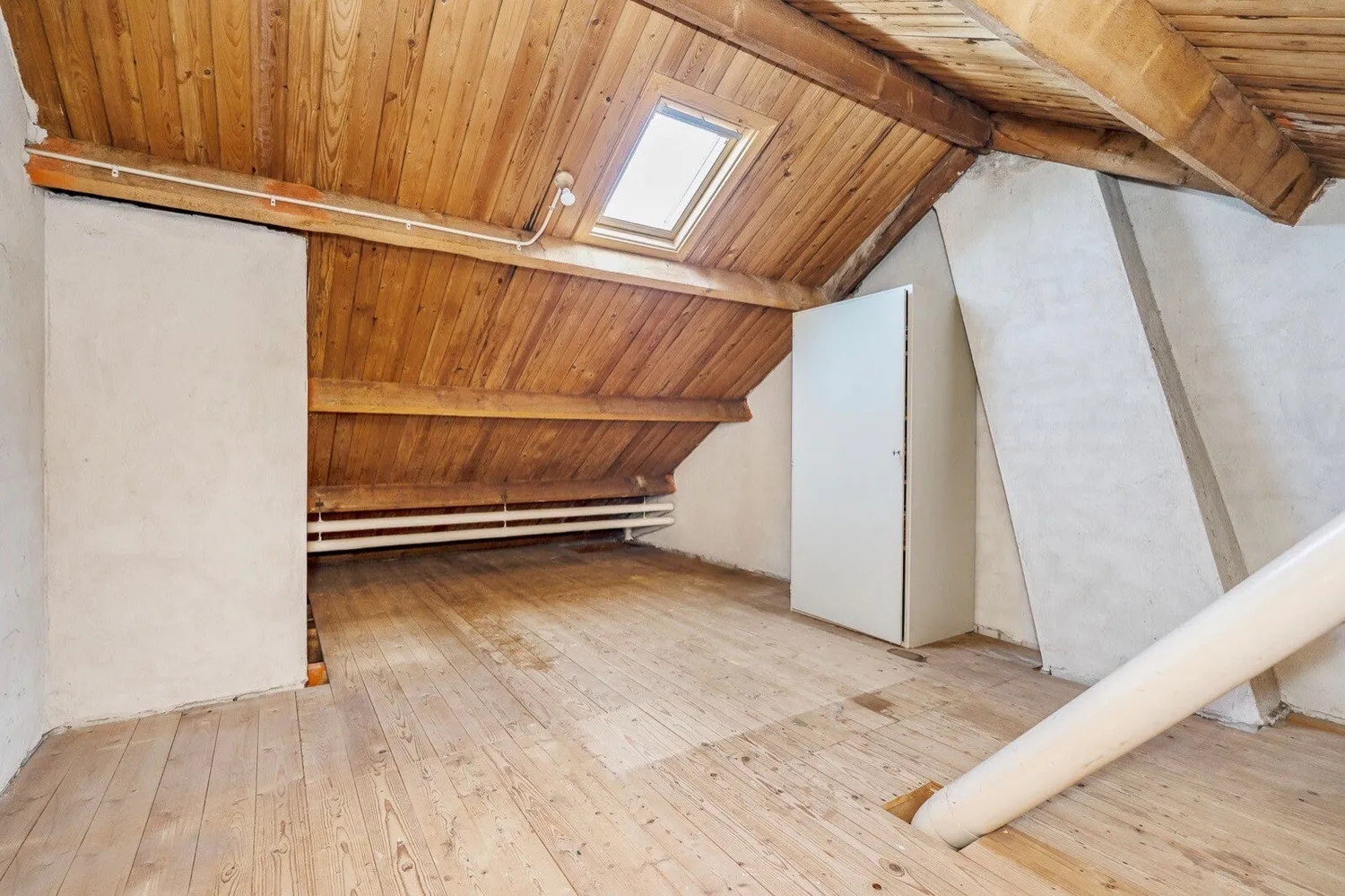 Zolder voor de verbouwing: houten schoten en leidingen in het zicht